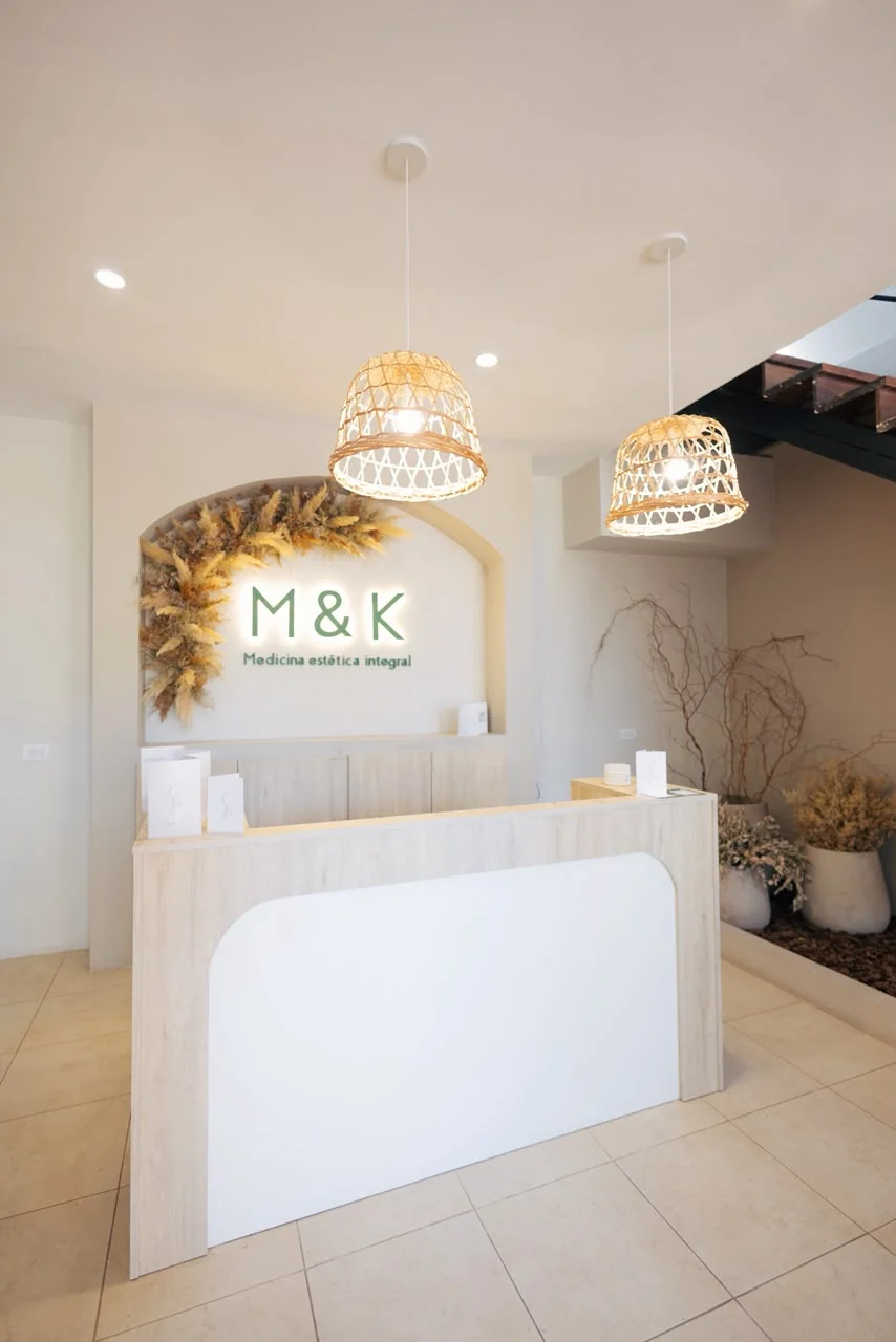 Recepción de M&K con su mostrador y el nombre de la clínica en la pared